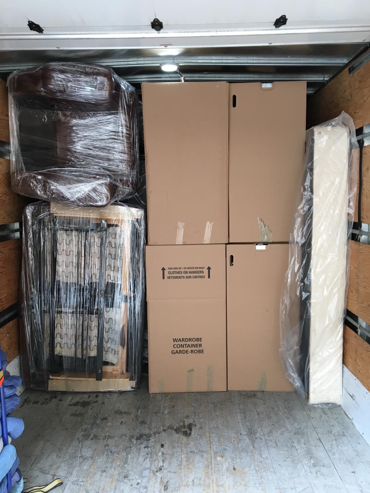 alt="A moving truck filled with big boxes and sofas wrapped in blankets for protection"