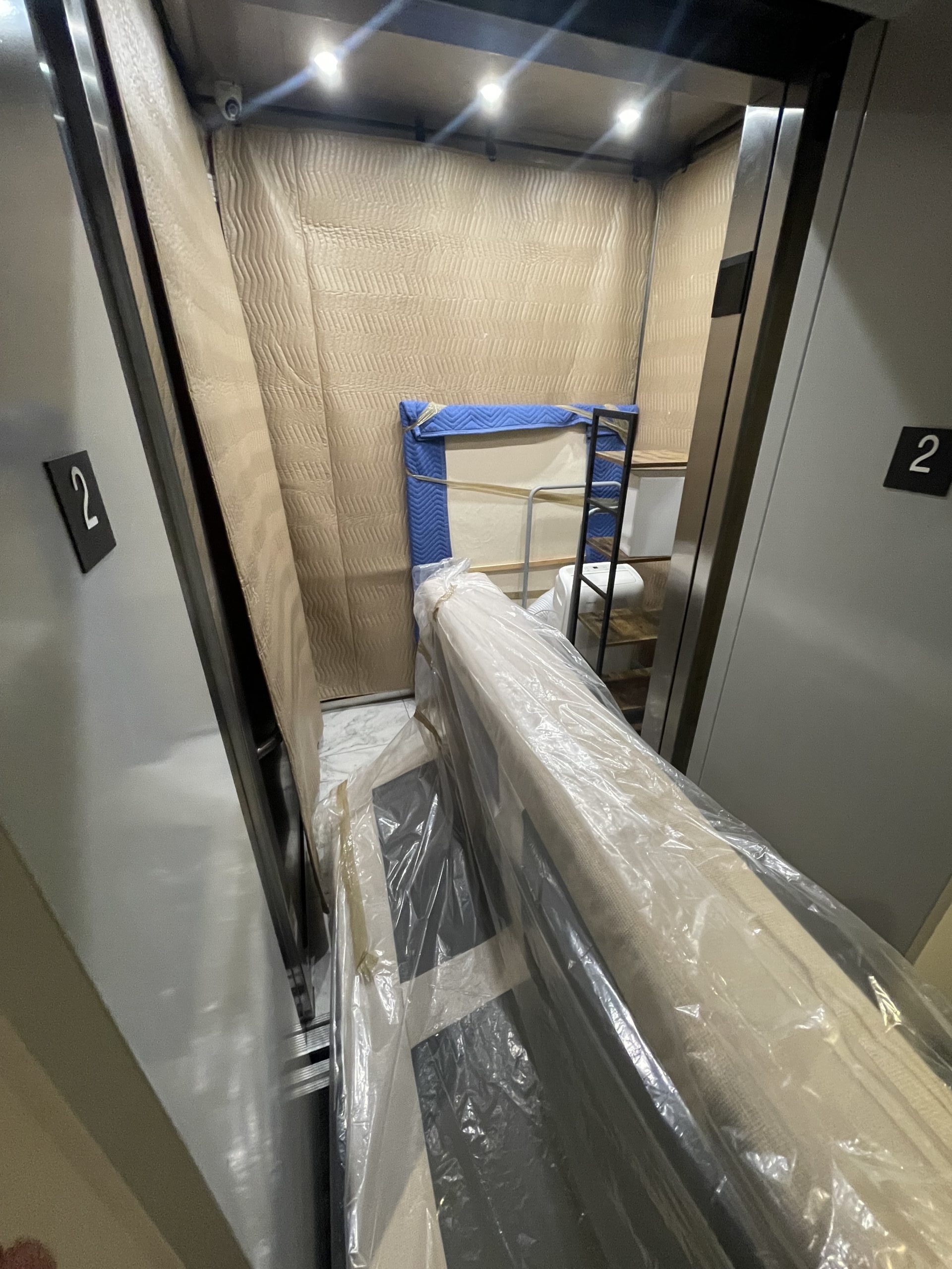 alt="A person placing furniture into an elevator for moving"