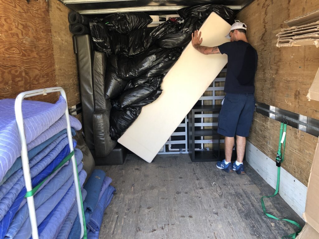 alt="A man placing furniture into a moving truck"