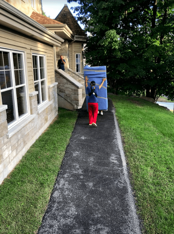 alt="Two men lifting a fridge together bringing it inside the house"