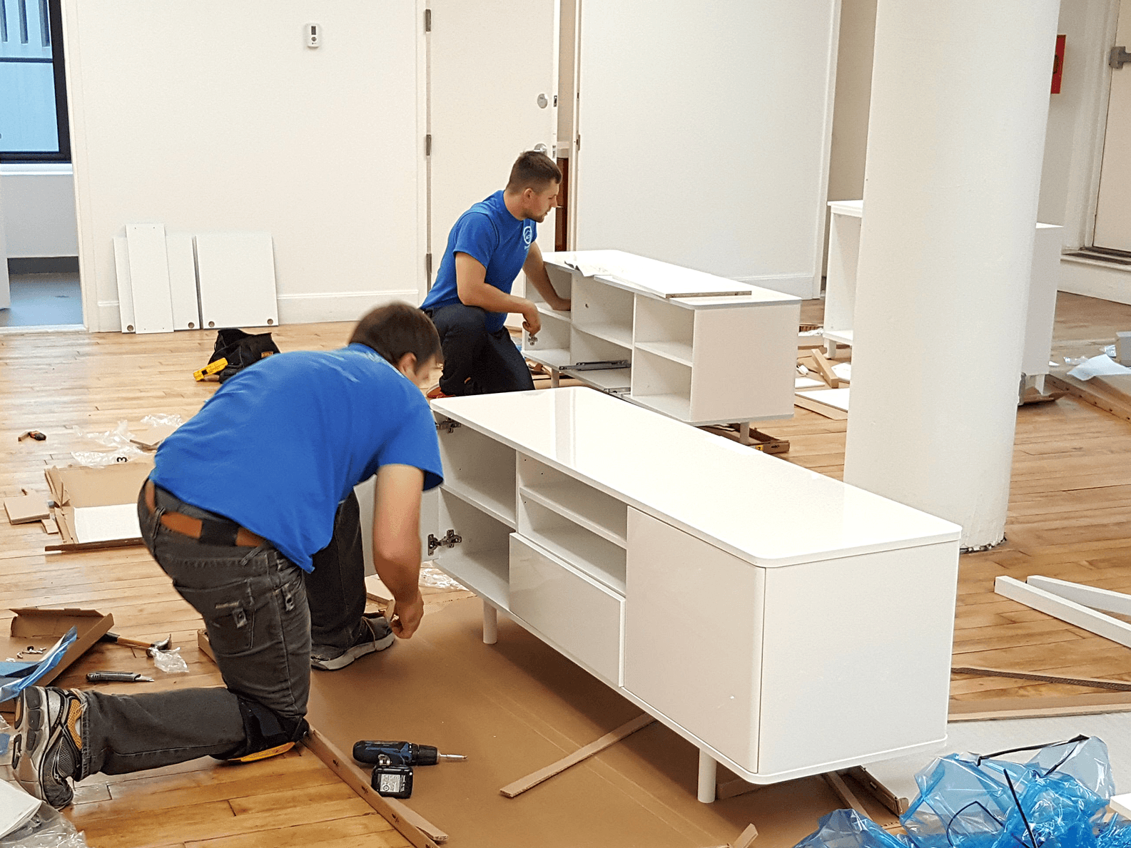 alt="Two men assembling a wooden tv stand together"